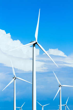 A modern technology wind turbine farm collecting energy with a blue cloudy background.