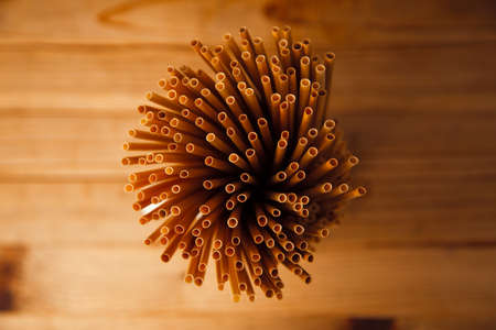 Ecologically friendly and biodegradable wheat straws on top of a rustic wooden table background.の写真素材