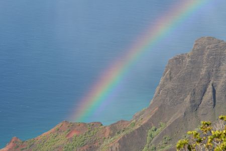 A rainbow stretches from the clouds to the sea.の写真素材