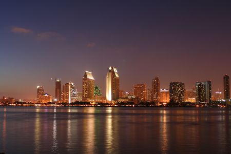 A cityscape in the even with lights reflected in water.の写真素材