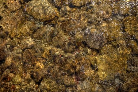 Yellow rocks at the bottom of a stream with water rushing over them. の写真素材