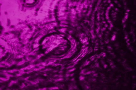 Dark purple water with multiple ripples on its surface.の写真素材