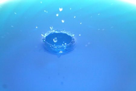 A crown of water rising out of a blue liquid.の写真素材