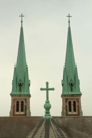 A cross on a church with two steples in the background.の写真素材