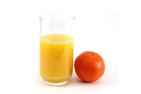 Glass of orange juice with oranges on the side.の写真素材
