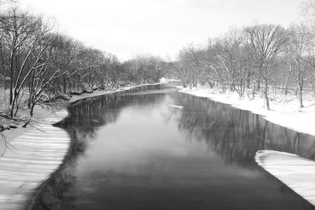 An icy river lowing through a winter landscape.の写真素材