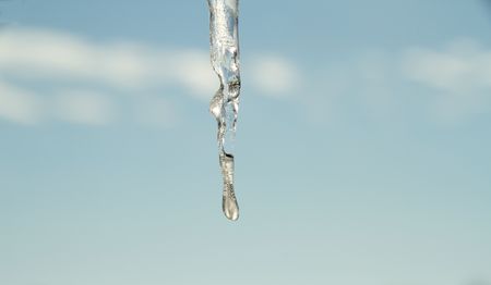 Icicles hanging with a blue ski in the background.の写真素材