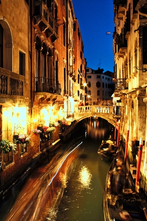 A restaurant lit up at night along a Venice canal.の写真素材