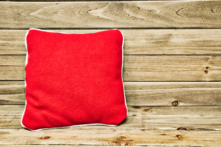 A red pillow propped up against a wood background.の写真素材