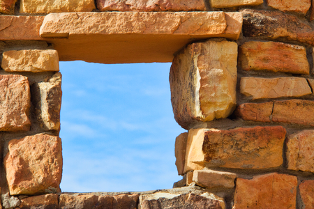 Looking through a window in the ruins of a desert dwelling to a blue skyの写真素材