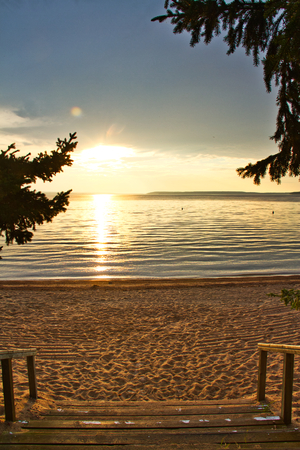 Stairs leading down to a beach with the sun setting over Waskesiu Lake in Prince Albert National Park of Canada.の写真素材