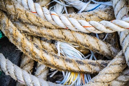 Nautical background of a detail of old frayed boat rope twisted in a pile.の写真素材