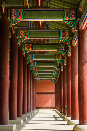 The repetition of columns at the Gyeongbok Royal Palace in Seould, South Korea.  The red columns with ornate ceiling draws the viewers eyes to the far end of the room.のeditorial素材