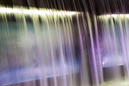 A waterfall flowing at night with purple lights illuminating it.の写真素材