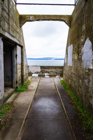 Abandoned ruins of an old costal artillery emplacement with rail road tracks leading to viewer through the image.の写真素材