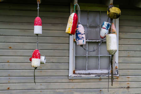 Fishing buoys hung in front of the windows of a cottage.の写真素材