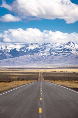 A long, straight road heading into the distant mountains in Idaho.の写真素材