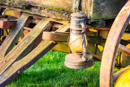 An old antique lantern handing on the side of a wagon in morning sunlight.の写真素材
