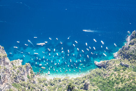 Looking down at a cove of the bright blue waters of the Mediterranean Sea with boats at anchor on a bright sunny day.の写真素材