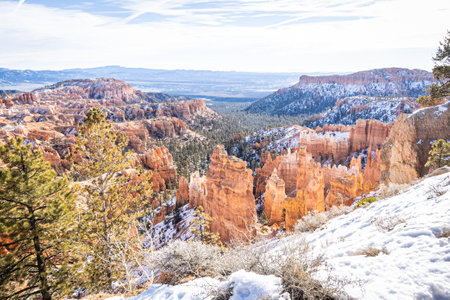 Bryce Canyon accented in freshly fallen snow and distant mountains and brilliantly colored orange cliffs.の写真素材