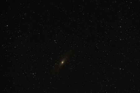 The Andromeda Galaxy glows softly in the night on a starry background.の写真素材
