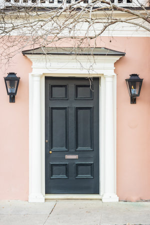 A colonial era door with gas lanterns and a mail slot on a pink house.の写真素材