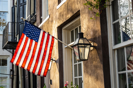 An American Flag hanging outside of a colonial era home in morning light.の写真素材