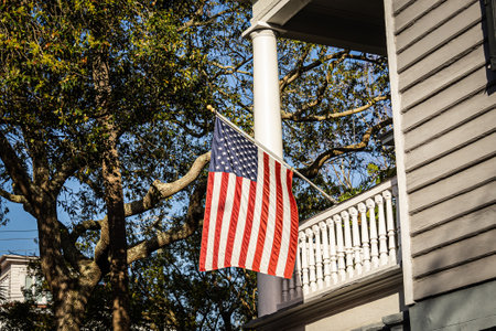 A patriotic display of an American Flag hanging on the side of a home in direct sunlight.の写真素材