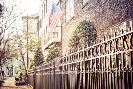 An American Flag hanging outside of a colonial era home in morning light.の写真素材