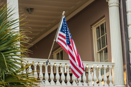 An American Flag hanging outside of a colonial era home in morning light.の写真素材