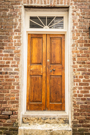 Double wooden doors on the front of a brick home with a wndow ove the door.の写真素材