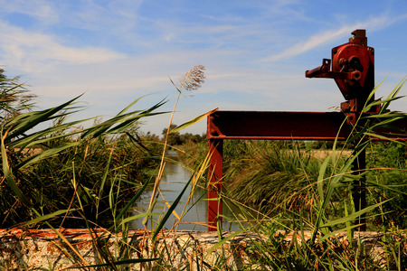 A creek in between the area of ??Montpellier, France, with a red old sluice mechanism in the foreground.の写真素材
