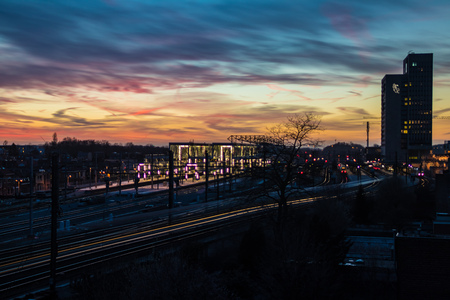 Very colorful and contrasted sky at sunset from above Ghent Sint Pieters, the main train station in Ghent, Belgium. Lights of the train passing by in the foreground low shutter speed.の写真素材