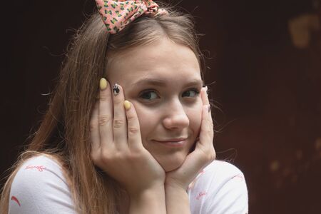 A young pretty European girl holds a hand in her face