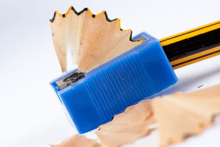 A pencil sharpener is doing its job. Shaving comes out from the sharpener. Stationery object close upの写真素材