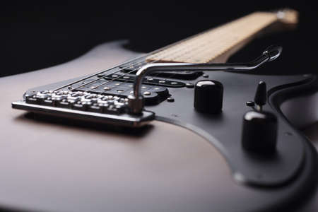 Elegant electric guitar on black background close up point of view showing larger part from body with humbucker pickups to head with silver tremolo and black pickguard and knobsの写真素材
