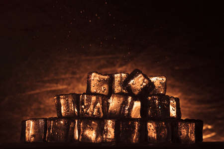 Ice cubes pile melting on a warm abstract background with water drops falling over itの写真素材