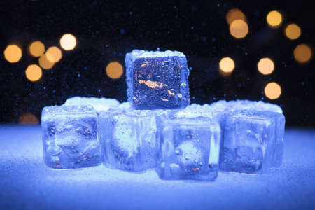 Wet ice cubes on a snow surface and garlands backgroundの写真素材