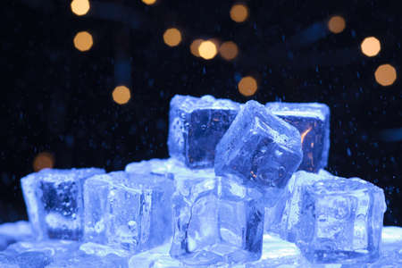 Bowl of ice with water drops falling over and garlands in the backgroundの写真素材