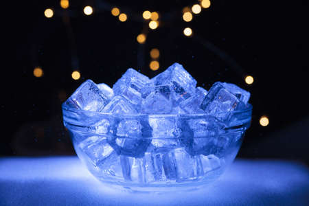 Bowl of wet ice with lights in the backgroundの写真素材