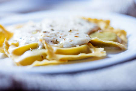 Ravioli fresh pasta dish with cheese sauce and oregano served on a white plateの写真素材