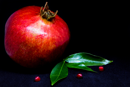 Pomegranate on a dark background with slices and green leaves, copyspaceの写真素材