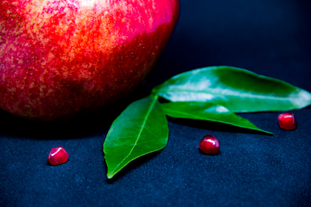 Pomegranate on a dark background with slices and green leaves, copyspaceの写真素材