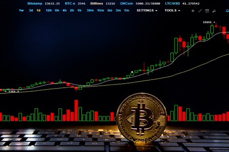 Bitcoin gold coin on a keyboard and focused chart background. Virtual cryptocurrency concept. Mining...