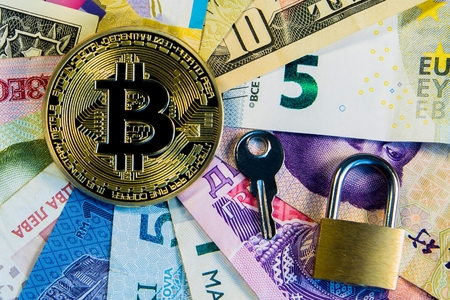 Cryptocurrency conceptual image of bitcoin internationalism and safety. Security bitcoin Physical coin bitcoin on the banknotes of different countries near the golden lock and key.の写真素材