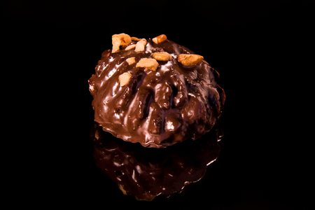Chocolate cake on a black mirror surface sprinkled with nut chips with a dark backgroundの写真素材