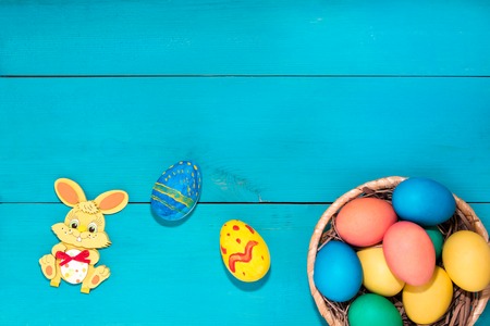 Easter bunny next to easter eggs on a blue wooden background