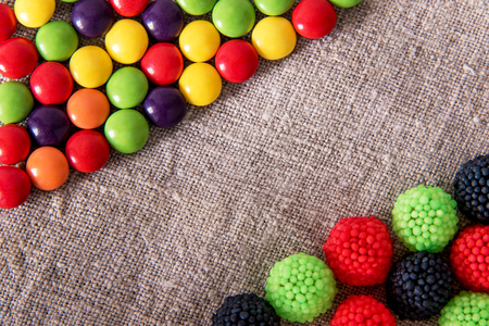 Delicious chocolate candy in a colored glaze with color fruit sweets on a gray textural fabric with copyspaseの写真素材