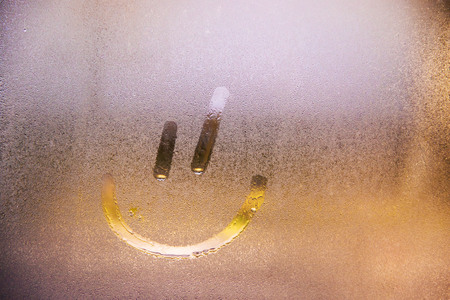 Foggy glass on window with drawn Smiley happy concept photo with copyspaceの写真素材
