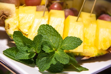 Plate with fruit sliced grapes, pineapple and green mintの写真素材